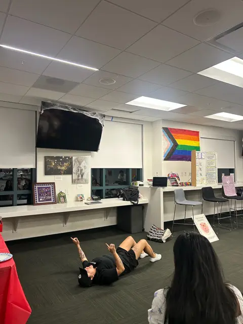 A student lying on the floor demonstrating an activity during a meeting while others watch.