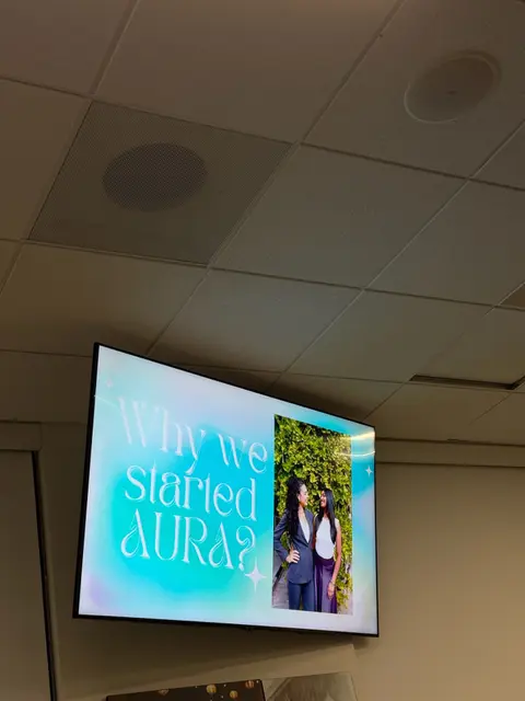 A presentation slide reading "Why we started AURA?" displayed on a classroom screen.