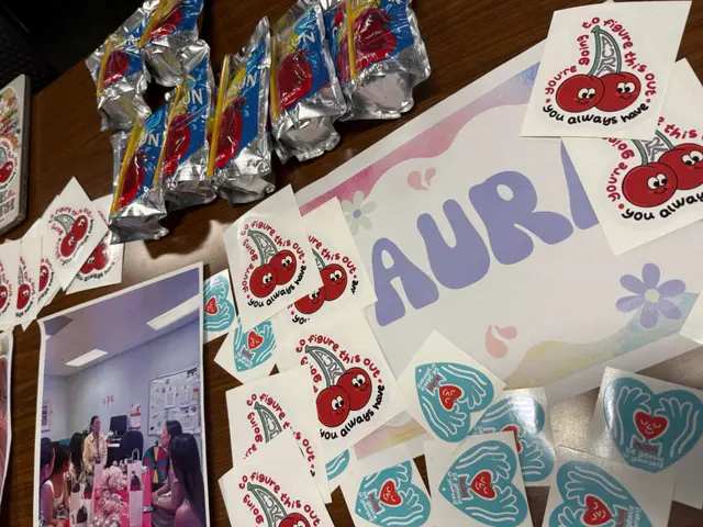 Packaged giveaways beside a hand-painted AURA sign covered in heart stickers.