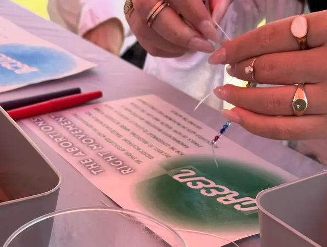Close-up of a student painting a design onto a pink tote bag.