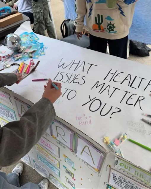 A student writing on a poster that asks "What health issues matter to you?"