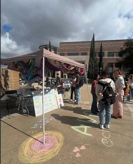 An outdoor tabling tent surrounded by chalk drawings on the pavement.