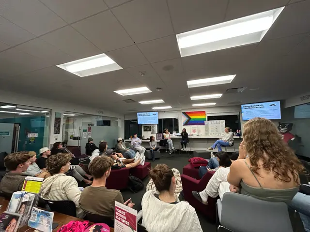 Students holding flyers while watching a presentation at a club meeting.