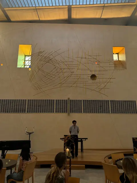 A speaker addressing the audience from the auditorium stage.