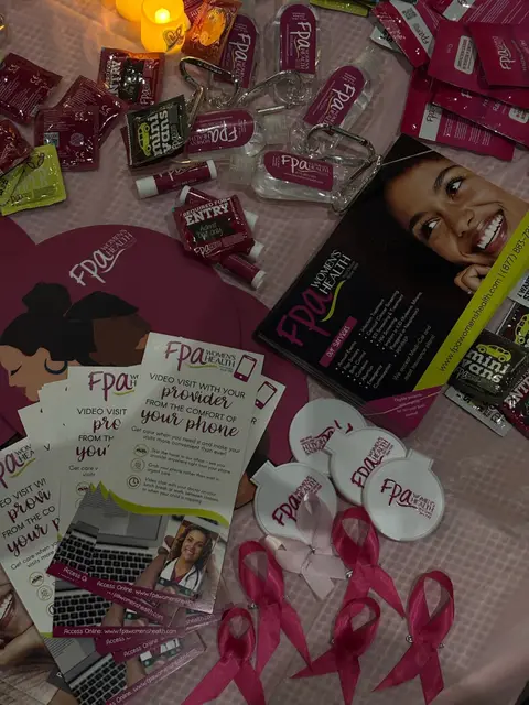 FPA Women's Health materials, pink awareness ribbons and giveaways spread across a table.