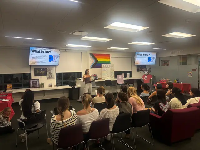 A classroom presentation with a slide reading "What is DV?" for Domestic Violence Awareness Month.