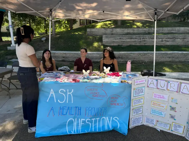 Students staffing an outdoor table under a hand-painted banner reading "Ask a health provider questions".